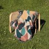 Woven blanket placed on a chair on grass, highlighting its colorful geometric design.