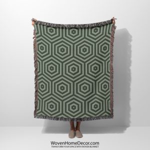 Woman holding a woven blanket with a modern hexagonal design in green and gray tones, with her face not visible.