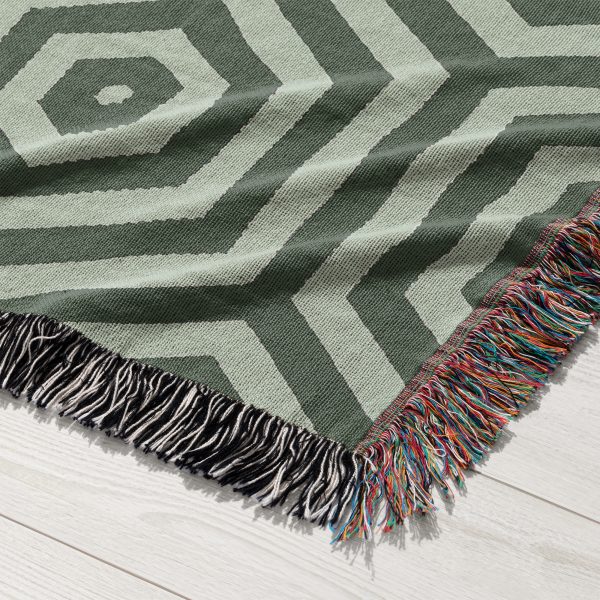 Close-up view of the woven blanket featuring a geometric hexagonal pattern in green and gray shades.