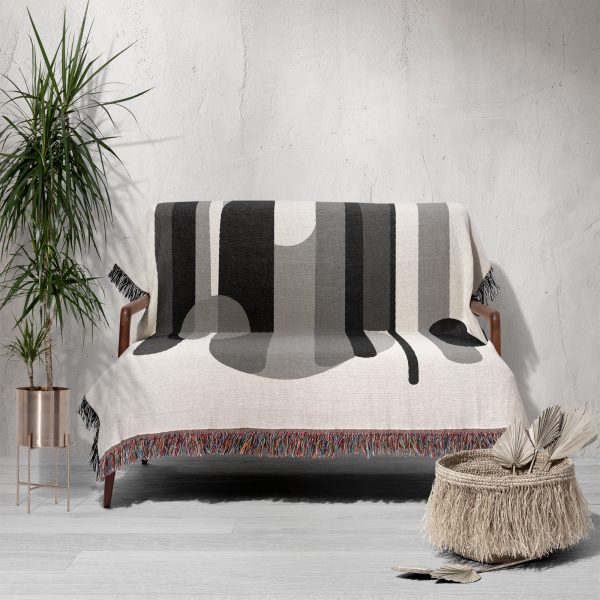 Sofa covered with a woven blanket in abstract monochrome patterns, adding a modern touch to the space.