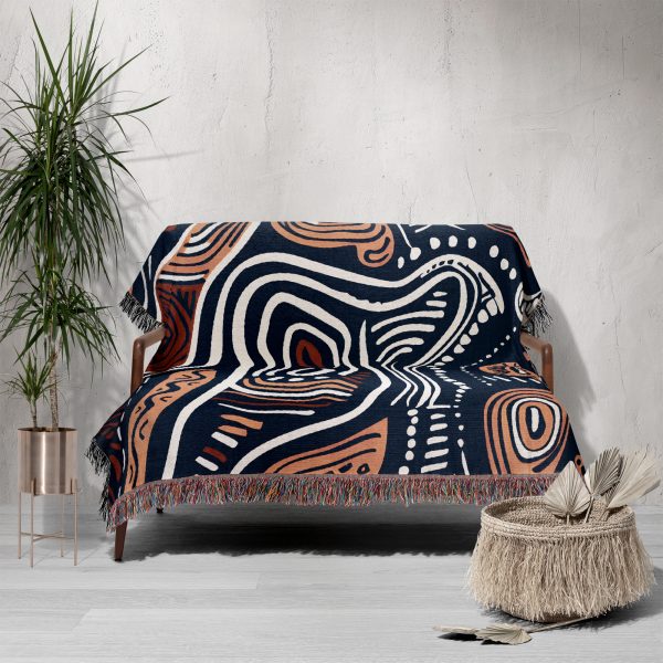 An organic-patterned woven blanket elegantly draped over a sofa in a minimalist space.