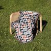 Scandinavian Chevron Harmony Woven Blanket placed on a chair outdoors on a grassy lawn.