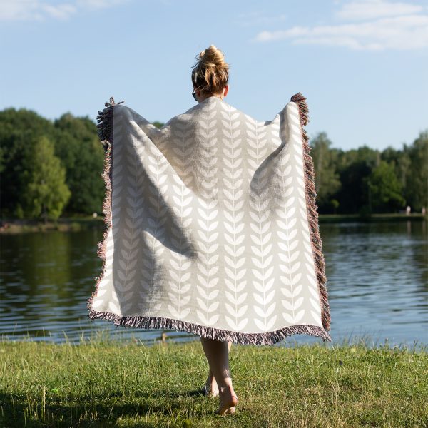 Back view of a person by a lake, wrapped in the Scandinavian Minimalist Leaf Woven Blanket.