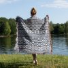 Back view of a person by a lake, wrapped in the Scandinavian Tribal Stripe Woven Blanket.