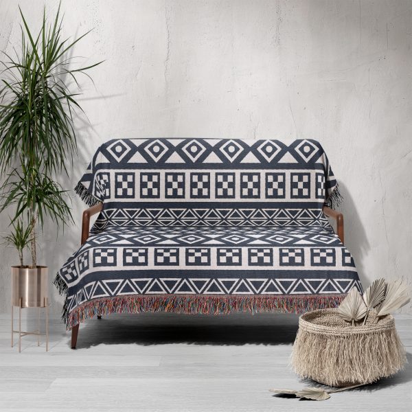 Scandinavian Tribal Stripe Woven Blanket draped over a sofa in a rustic setting.