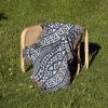 Scandinavian Tribal Stripe Woven Blanket placed on a chair outdoors on a grassy lawn.