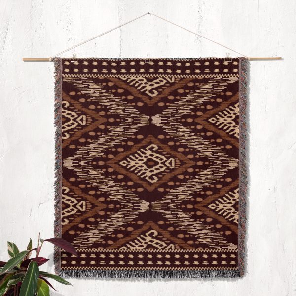 The tribal-patterned woven blanket displayed as a tapestry on a neutral wall.