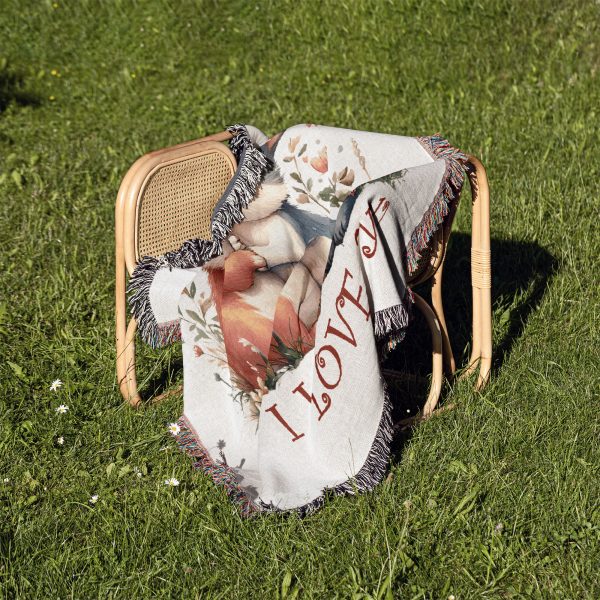 The Adorable Bunny Love blanket folded on a chair outdoors on a grassy background