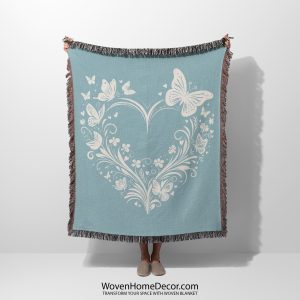 A woven blanket featuring a butterfly and heart motif, held up by a person.