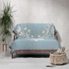 The woven blanket with butterfly and heart motifs draped over a sofa.