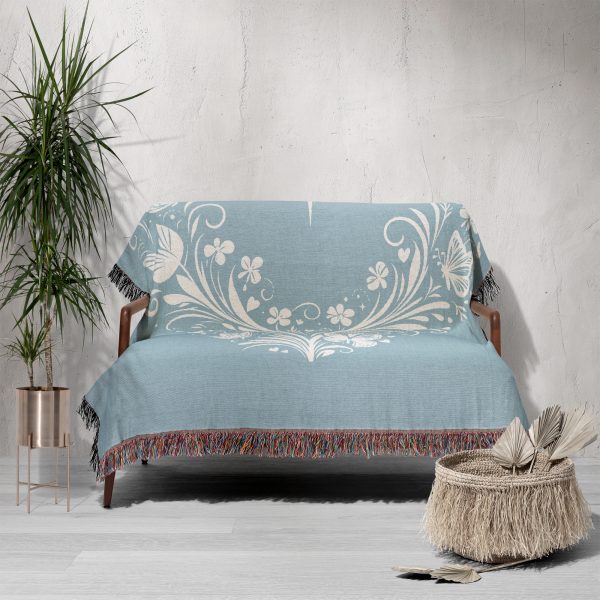 The woven blanket with butterfly and heart motifs draped over a sofa.