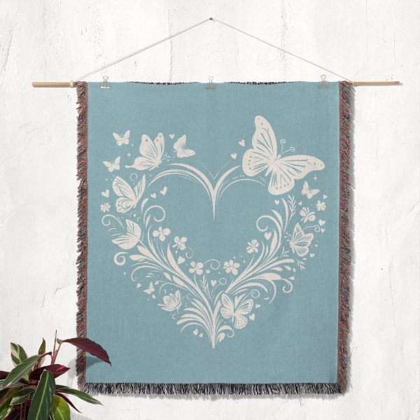 The woven blanket with butterfly and heart designs displayed as a wall tapestry.