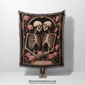 A woven blanket featuring a skeleton couple and roses, held up by a person