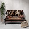 A woven blanket with a skeleton couple design draped over a sofa.