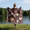 A person standing by a lake, draped in the Floral and Heart Dark blanket, view from behind