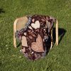 The Floral and Heart Dark blanket folded and placed on a chair outdoors on the grass