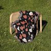 The Heart Pattern Woven Blanket folded on a chair placed on a grassy lawn.