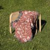 The Love Symbols Woven Blanket folded neatly on a chair outdoors, surrounded by grass.