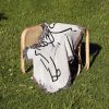 The Minimalist Love Sketch blanket folded and placed on a chair outdoors on the grass