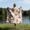 A person standing by a lakeside, draped in the Romantic Floral and Heart Motif blanket, view from behind