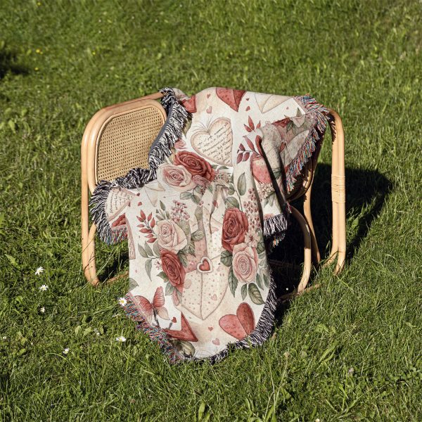 The Romantic Floral and Heart Motif blanket folded and placed on a chair outdoors, surrounded by grass