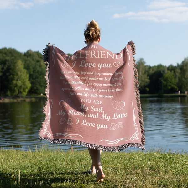 A woman by the lake, draped in the Romantic Girlfriend Woven Blanket, photographed from behind.