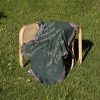 The To My Boyfriend Woven Blanket folded on a chair outdoors, surrounded by green grass.