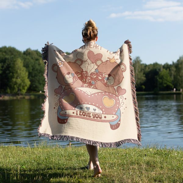 A person standing by a lake, draped in the Vintage Car Bears blanket, view from behind