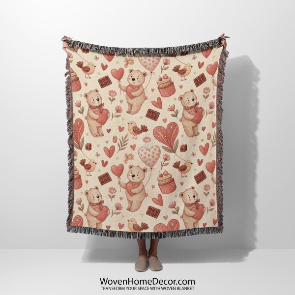 A Whimsical Bear and Balloon Love woven blanket, held up by an unseen person