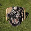 The woven blanket with skeleton skulls placed on a chair set on grass.